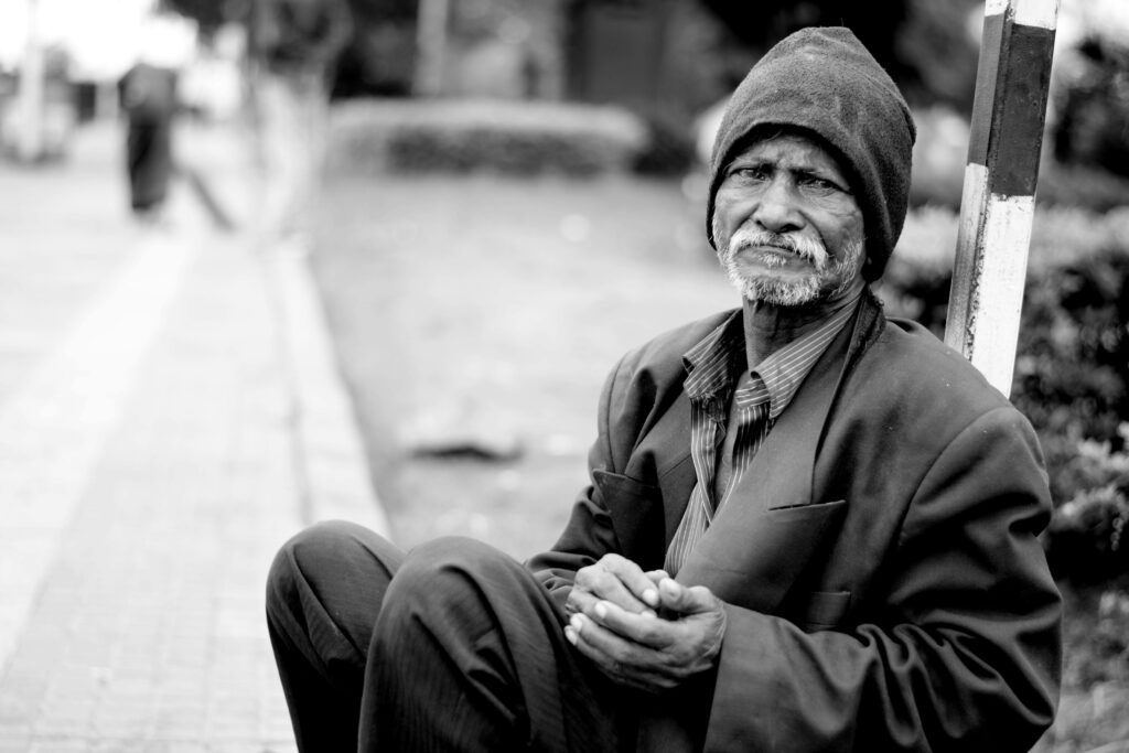pexels-photo-220365-220365 A black and white portrait of an elderly man sitting on the streets, expressing hardship and resilience.